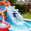 Parc aquatique gonflable 9-en-1 pour les enfants, maison gonflable avec glissades doubles, aire de saut, mur d'escalade, anneau d'ancrage, panier de basketball, doubles pistolets à eau et piscines peu profondes / de baignade - Amusement extérieur dans la cour