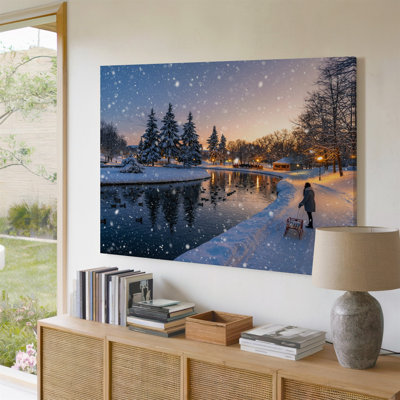Toile, paysage d'hiver serein représentant un parc couvert de neige au crépuscule avec de douces lumières rougeoyantes reflétant un étang gelé