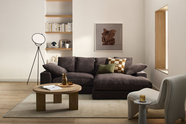 Comfortable brown corduroy sofa wood coffee table modern curved accent chair and wall art