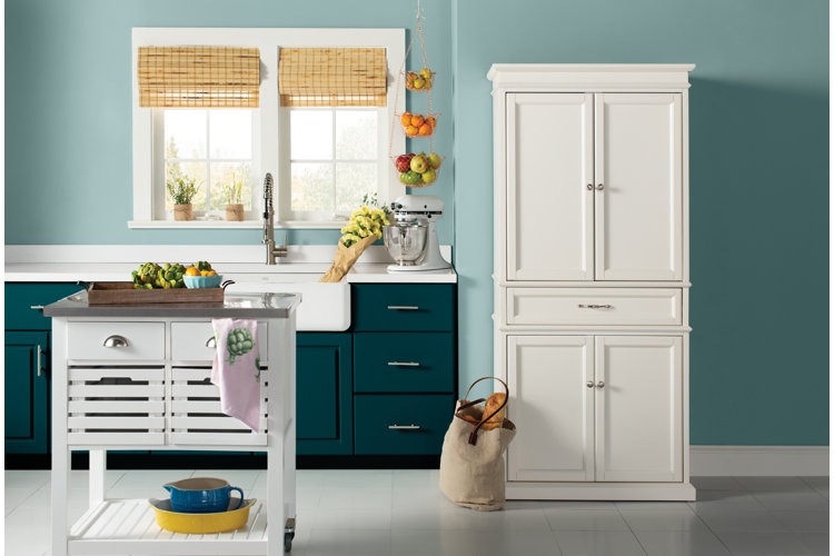 coastal kitchen with teal walls and a standalone storage hutch and kitchen island