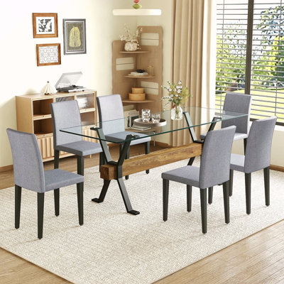 Ensemble de table et de chaises. Plateau de table en verre trempé de 79 po x 31,5 po avec pieds en métal noir en forme de X, traverse en panneau de fibres à densité moyenne à grain de bois texturé et doublé de chaises en lin et coton gris clair.
