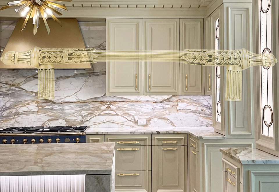Ornate brass cabinet pull with intricate floral detailing, displayed against a luxurious cream-colored kitchen featuring marble countertops and a gold range hood.