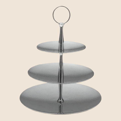 Three-tier silver serving stand with a circular handle on a cream background.