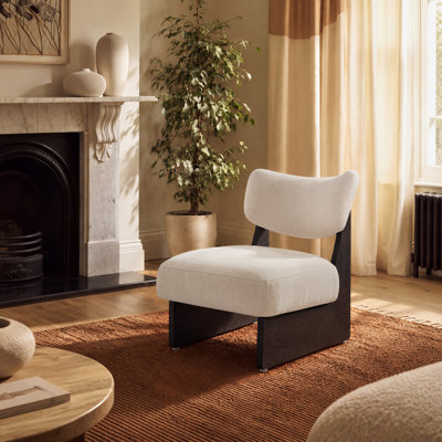 Fauteuil d'appoint moderne en tissu organique, avec dossier incurvé et structure sculpturale en bois noir.