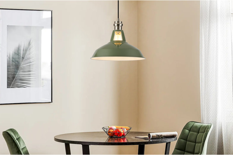 modern dining nook with round black table, green upholstered chairs, and green metal swag light