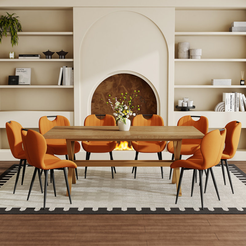 Ensemble de table et de chaises. Table de salle à manger en bois aggloméré de 71 po x 35,4 po avec table en X en forme de X. Comprend 8 chaises de salle à manger en tissu orange avec poignée intégrée. Cadre en métal noir.