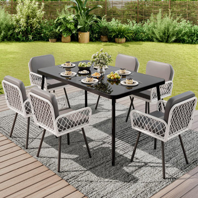 Ensemble de salle à manger d'extérieur 7 pièces en résine tressée résistante aux intempéries pour 6 personnes – Table en métal noir de 150 cm avec plateau en verre trempé, chaises pivotantes en rotin et coussins épais