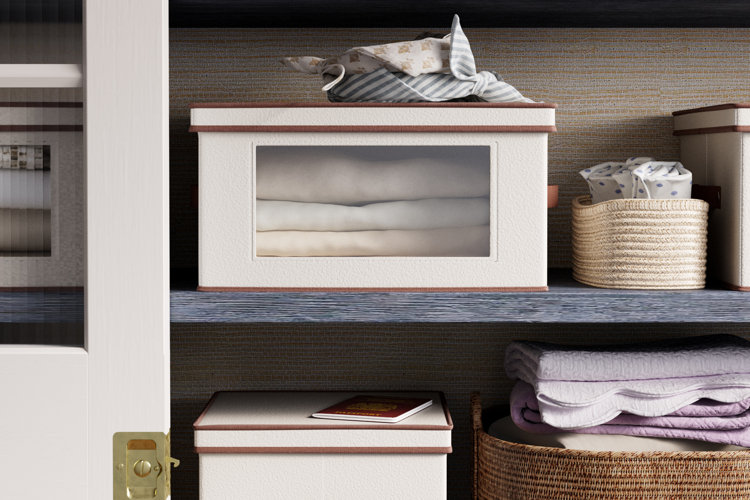 A linen closet with fabric and wicker baskets used to store sheets, quilts, and pillow shams.