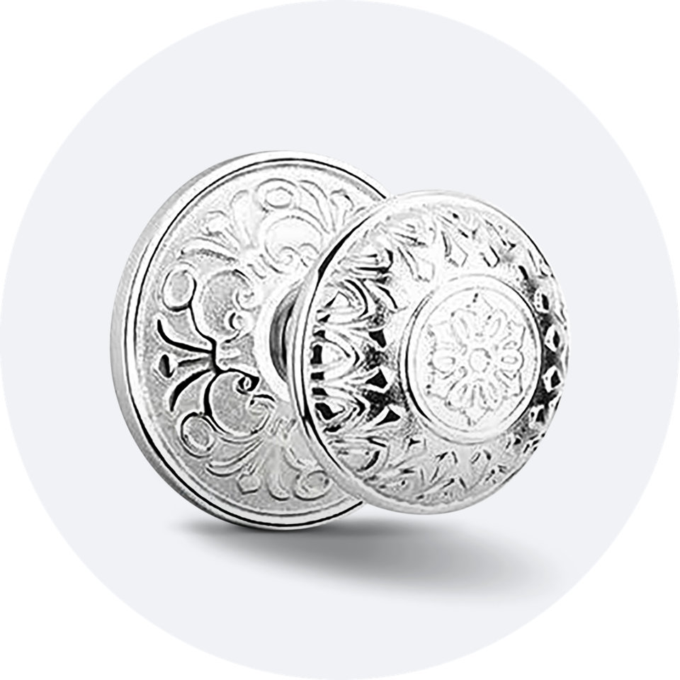 Ornate polished chrome round door knob with intricate floral detailing on a white background.
