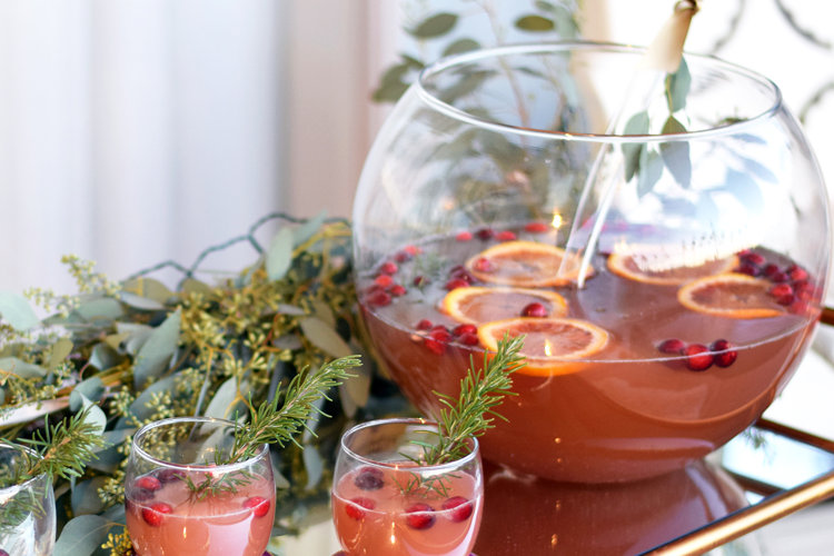 Batch cocktail in a punch bowl with orange and cranberry garnish.