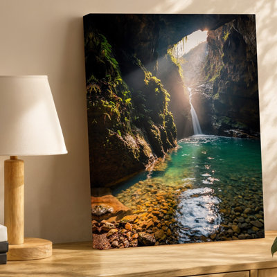 Toile, une magnifique grotte creusée illuminée par la lumière du soleil en cascade filtrant l'art mural à travers l'entrée rocheuse, créant une toile