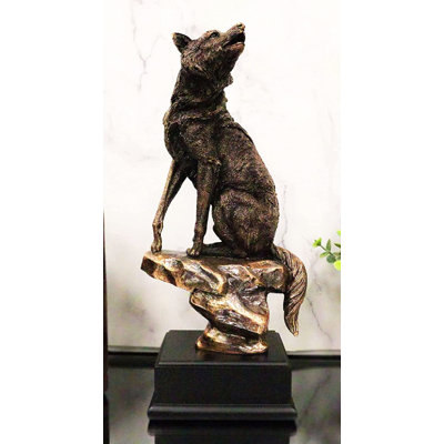 Statue de loup alpin Jonesha Woodlands Howling assis sur une falaise rocheuse