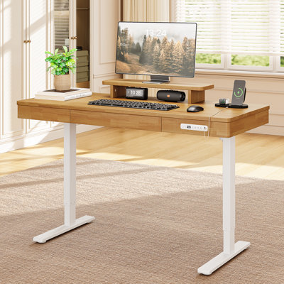 Bureau assis-debout en bois massif, 140 x 60 cm, réglable en hauteur électrique, avec tiroir compartimenté, tablette pour écran et prises électriques.