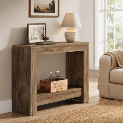 Table d'appoint noire et marron de 104 cm avec tablette de rangement inférieure, style ferme, en panneaux de particules, idéale pour les petits espaces et à placer derrière un canapé.