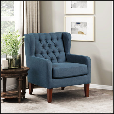 Fauteuil d'appoint classique à oreilles avec revêtement capitonné moelleux et pieds en bois massif, parfait pour un confort luxueux dans n'importe quel salon.