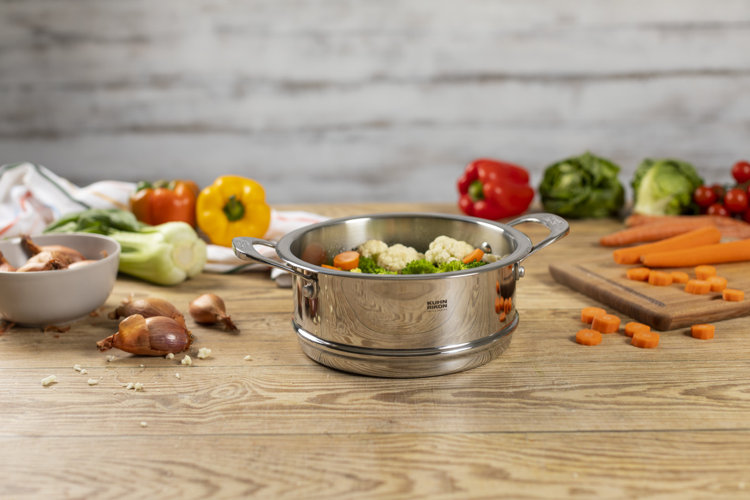 a stainless steel steamer basket with vegetables in it