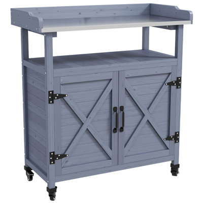 Table de rempotage grise en bois avec rangement intégré. Plateau en aluminium. Roulettes en caoutchouc pour un déplacement facile. Résistante aux intempéries. Parfait pour le jardinage biologique. Dimensions : 84,8 cm (l) x 40,6 cm (p) x 95,2 cm (h). Compartiment de rangement extérieur. Conception résistante aux intempéries.