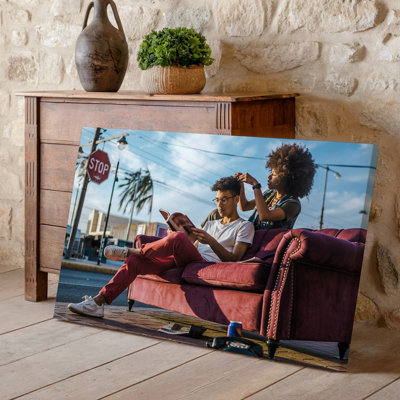 Toile «A Vibrant Urban Scene Captures A Relaxed Moment On A Wall Art Sunlit Day» mettant en vedette un jeune homme assis sur un papier peint rétro pour art mural moderne
