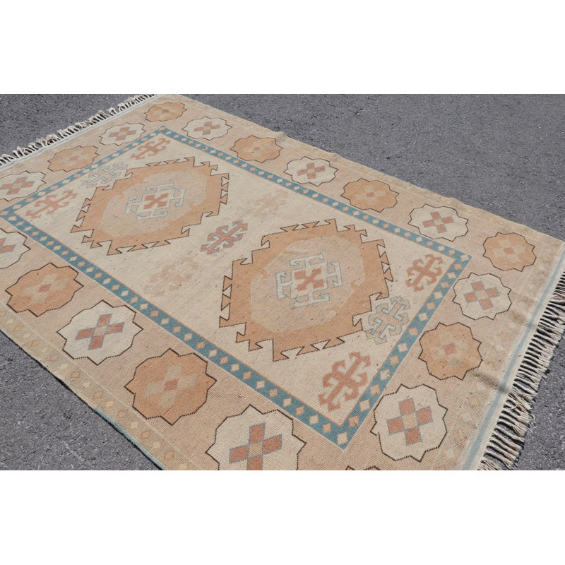 Tapis turc rétro beige doux et bleu avec des tons pastel et des motifs géométriques, idéal comme décoration intérieure unique en tant que tapis tissé à la main