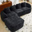 Canapé de coin comprimé en chenille noire, garni de mousse souple haute élasticité, incurvé et doté de quatre coussins décoratifs. Parfait pour le salon et la chambre. Assise mi-ferme, support par ressorts.