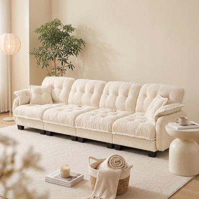 Canapé nuage 4 places beige crème en chenille, avec coussins capitonnés et finitions à pompons.