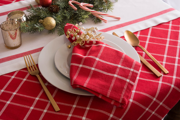 Christmas dining table with red gingham tablecloth and matching cloth napkins.