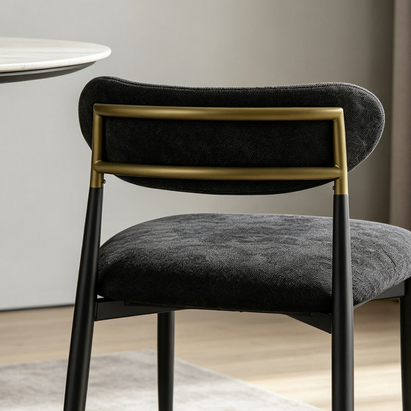 Chaise de salle à manger moderne et minimaliste, revêtue de tissu noir, avec dossier cylindrique incurvé et pieds en métal.