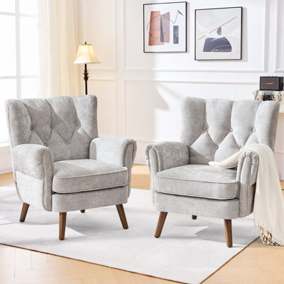 Fauteuil à oreilles capitonné avec accoudoirs roulés et coussins épais.