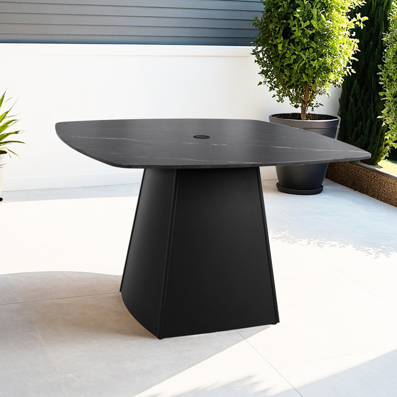 Table carrée arrondie d'extérieur moderne 112 x 112 cm, en pierre frittée noire, fini rouille, idéale pour les petits espaces. Pied central évasé de 112 cm pour quatre personnes. Parfait pour les réceptions sur la terrasse.