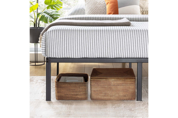 two woven storage baskets under a metal bed frame