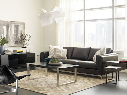 An industrial-style living room with a black sofa and white decorative pillows.