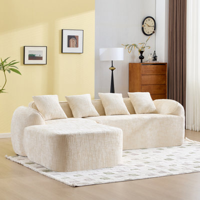 Beige Chenille L-Shaped Compressed Sofa That Goes Well With Any Living Room. It Features High-Elastic Sponge For A Comfortable Sitting Feel,  Curved Armrests And Four Throw Pillows.
