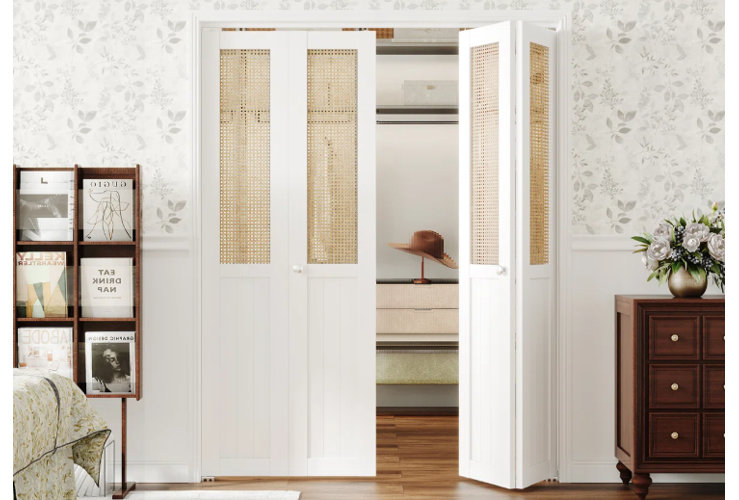 white bifold closet doors with woven panel inserts surrounded by floral wallpaper and wooden furniture
