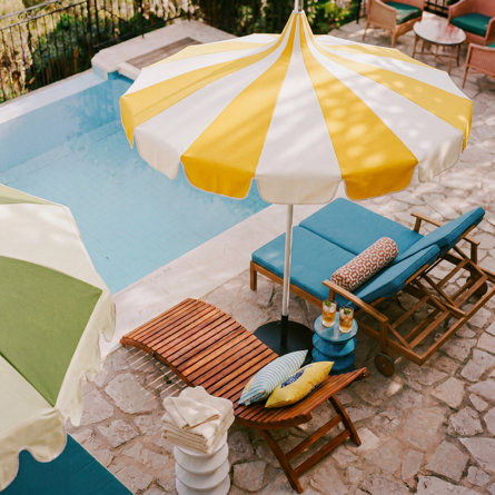 Poolside patio with striped umbrellas and lounge chairs.