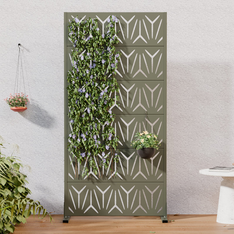 Olive green metal privacy screen with a geometric Y-shaped laser-cut pattern decorated with climbing vines.