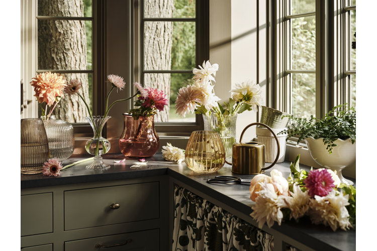 Dark green cabinets and black countertop with colored glass vases and a mix of flowers