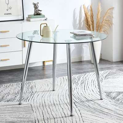 Un plateau de table en verre avec une table de salle à manger circulaire minimaliste moderne avec des pieds en métal galvanisé.