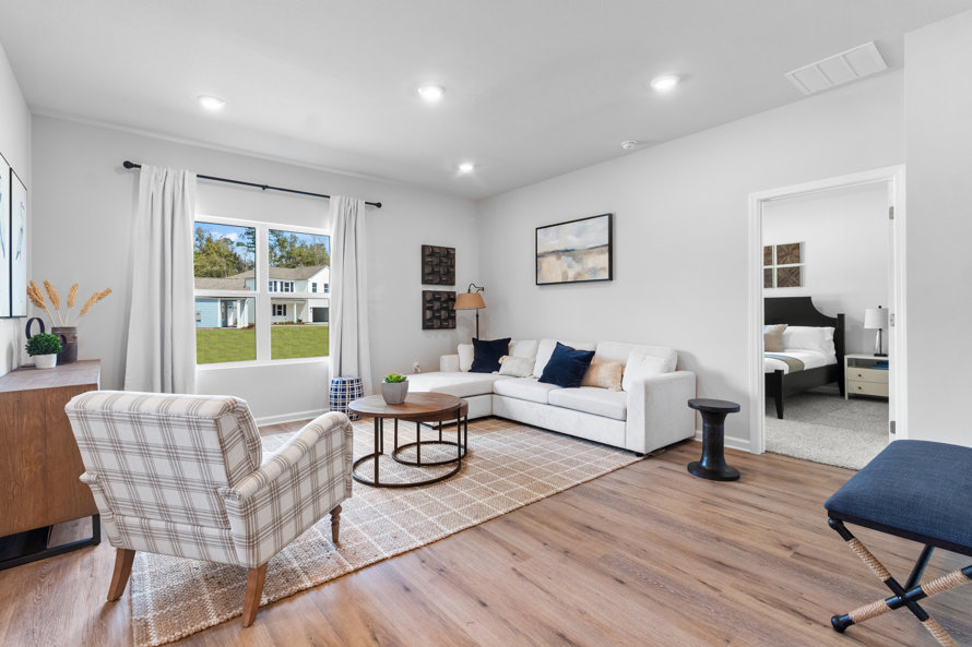 Living room with beige plaid armchair, white sectional sofa, and layered round coffee tables.