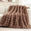 Brown faux fur throw blanket with a textured bubble wave pattern draped over a light-colored sofa.