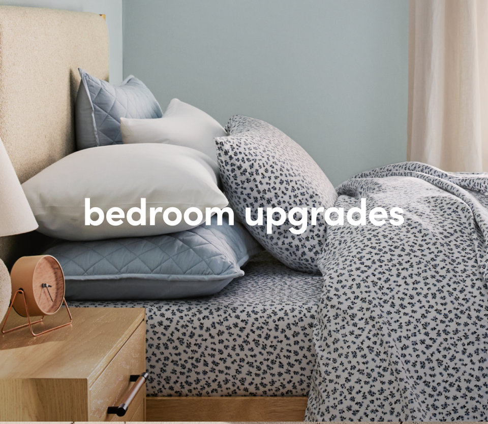 A cozy bedroom with spotted bedding, wooden nightstand, and warm lighting.