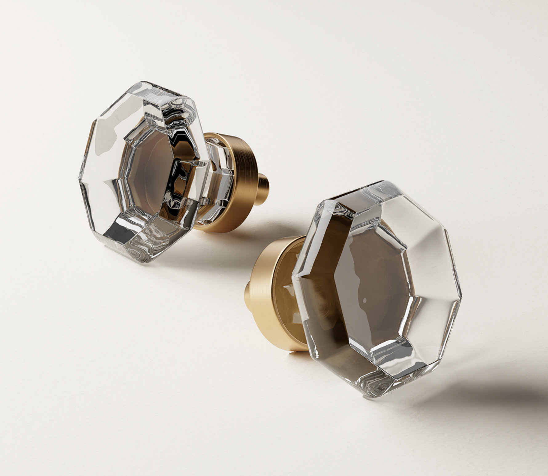 Two clear octagonal glass door knobs with gold bases.