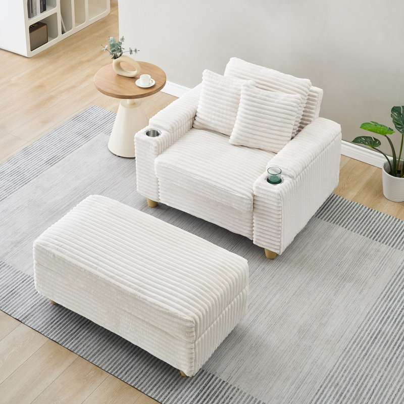 Canapé blanc simple en velours côtelé avec un coussin, deux coussins décoratifs, un repose-pieds et deux espaces de rangement.