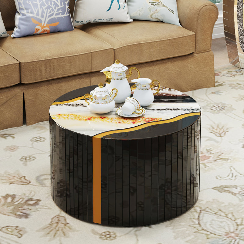 Table basse cylindrique noire et noire en verre noir avec miroir effet poudre dorée et motif de marbre sur la table d'appoint.