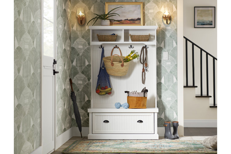 Entryway with a white hall tree that has a built-in bench, under-bench storage, wall hooks, and overhead storage cubbies.