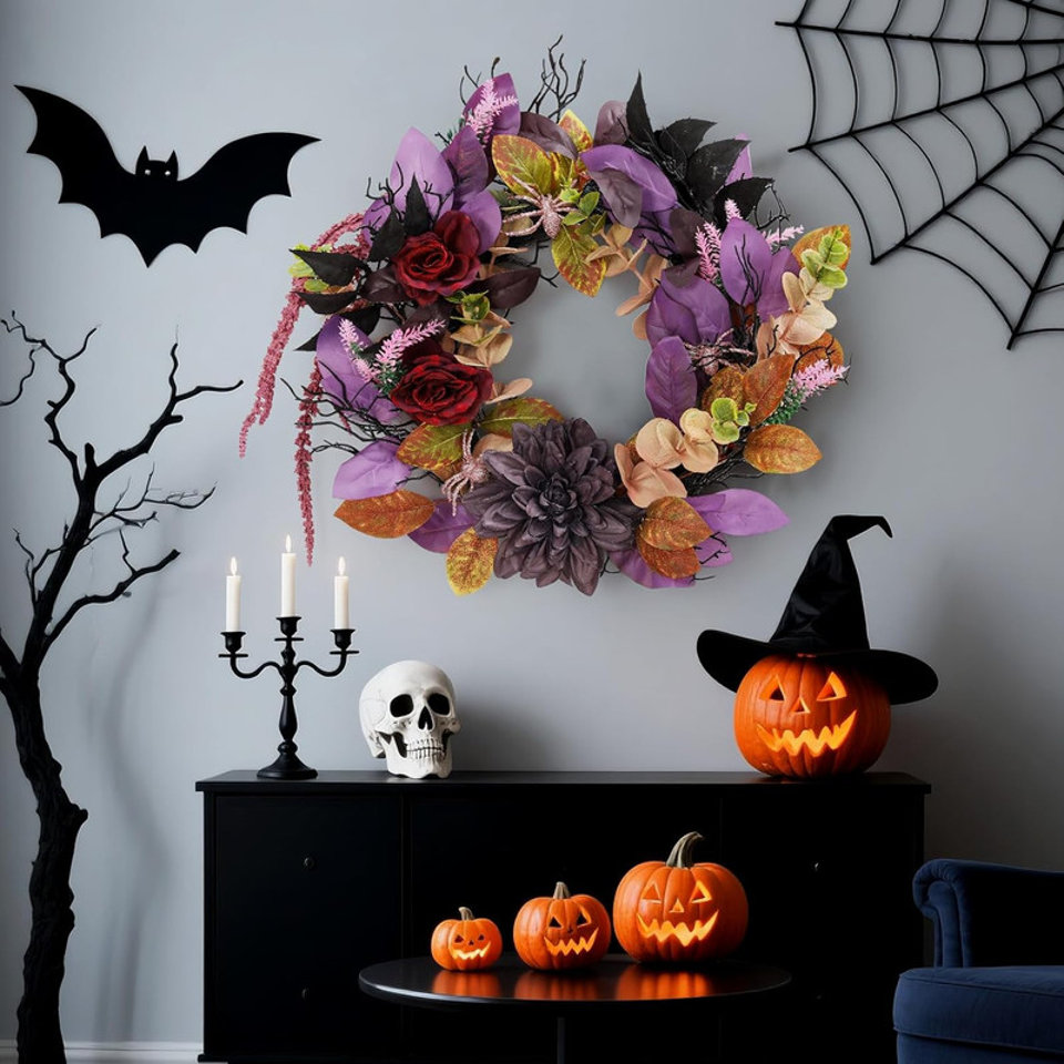 Halloween decorative wreath featuring purple and dark red faux flowers and leaves, hanging on a wall above a black console table with a skull, candle holder, and carved jack-o'-lanterns.
