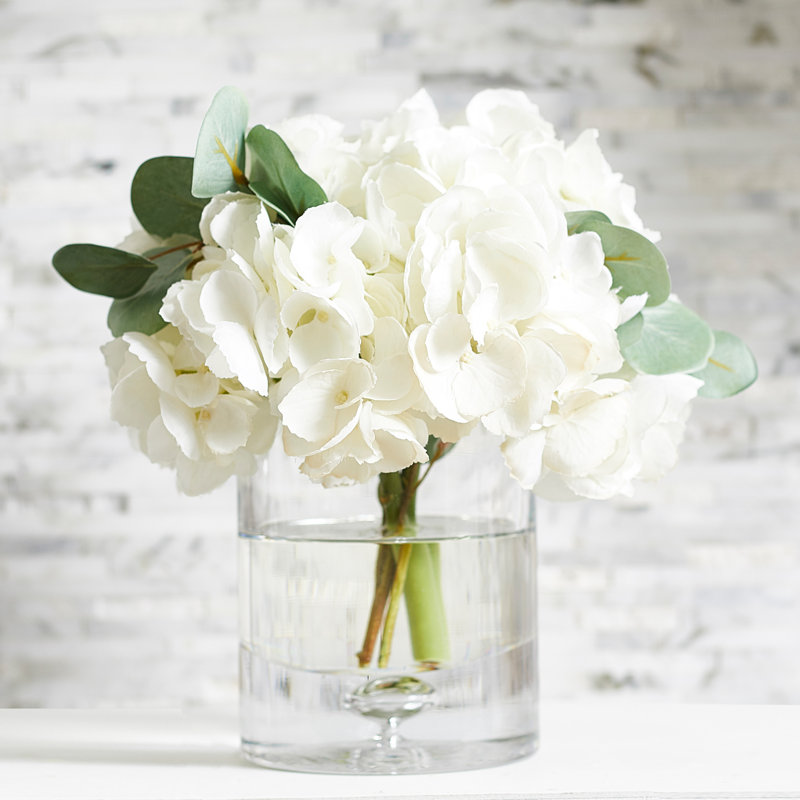 Ensemble d’hortensias blancs dans un vase cylindrique en verre