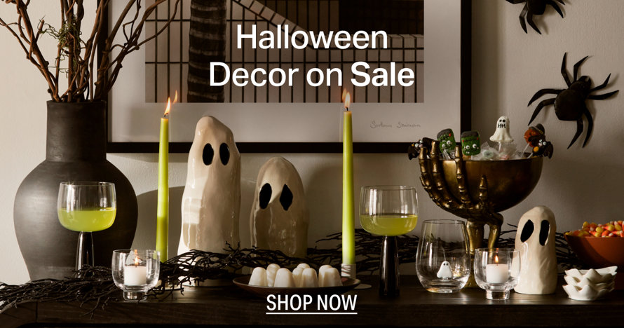 Halloween Decor on Sale, shop now to browse a selection of ghost figurines, candle holders, and festive seasonal accents arranged on a table.