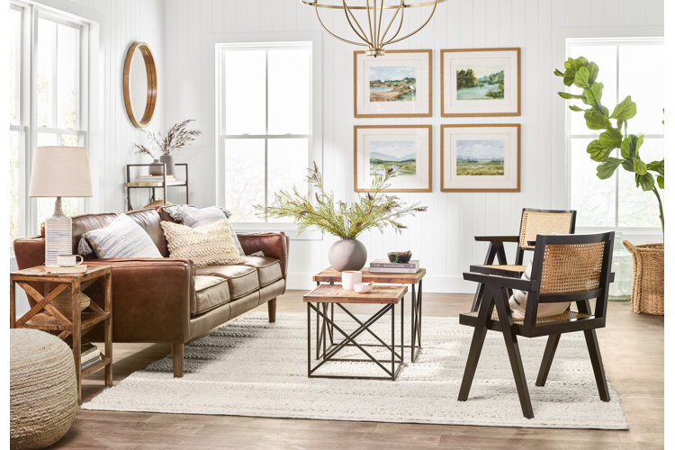 coastal farmhouse living room with a leather sofa, nesting coffee tables, and two cane accent chairs