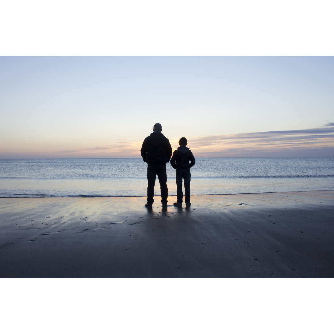 Vater und Sohn beobachten den Sonnenaufgang