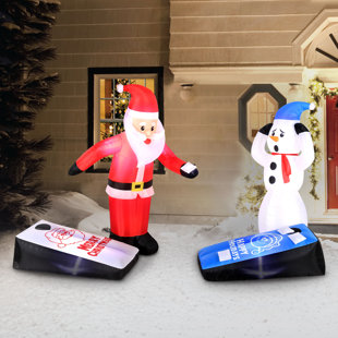 Père Noël et bonhomme de neige jouant au jeu de cornhole gonflable